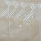 14ct gold huggies with salt water pearl charms hanging on a jewellery hanger